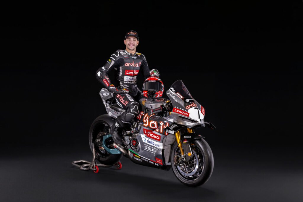 Piloto del Aruba.it Racing Ducati junto a su Panigale V4 R plateada