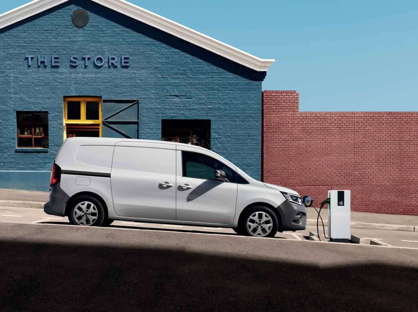Renault Kangoo Van E-Tech electric cargando junto a un punto de recarga