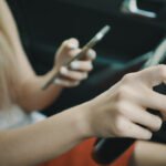 Conductora mirando el móvil al volante, primera causa de multa por distracciones según la DGT