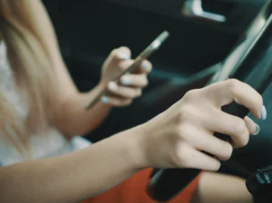 Conductora mirando el móvil al volante, primera causa de multa por distracciones según la DGT