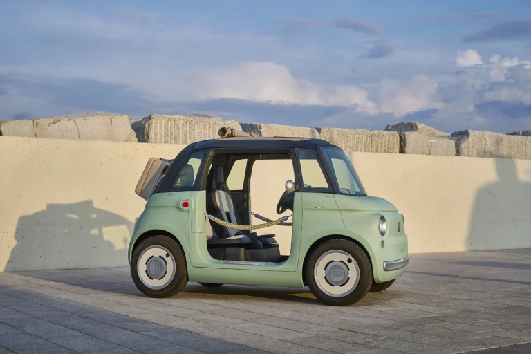 Fiat Topolino verde visto de lado junto a un muro