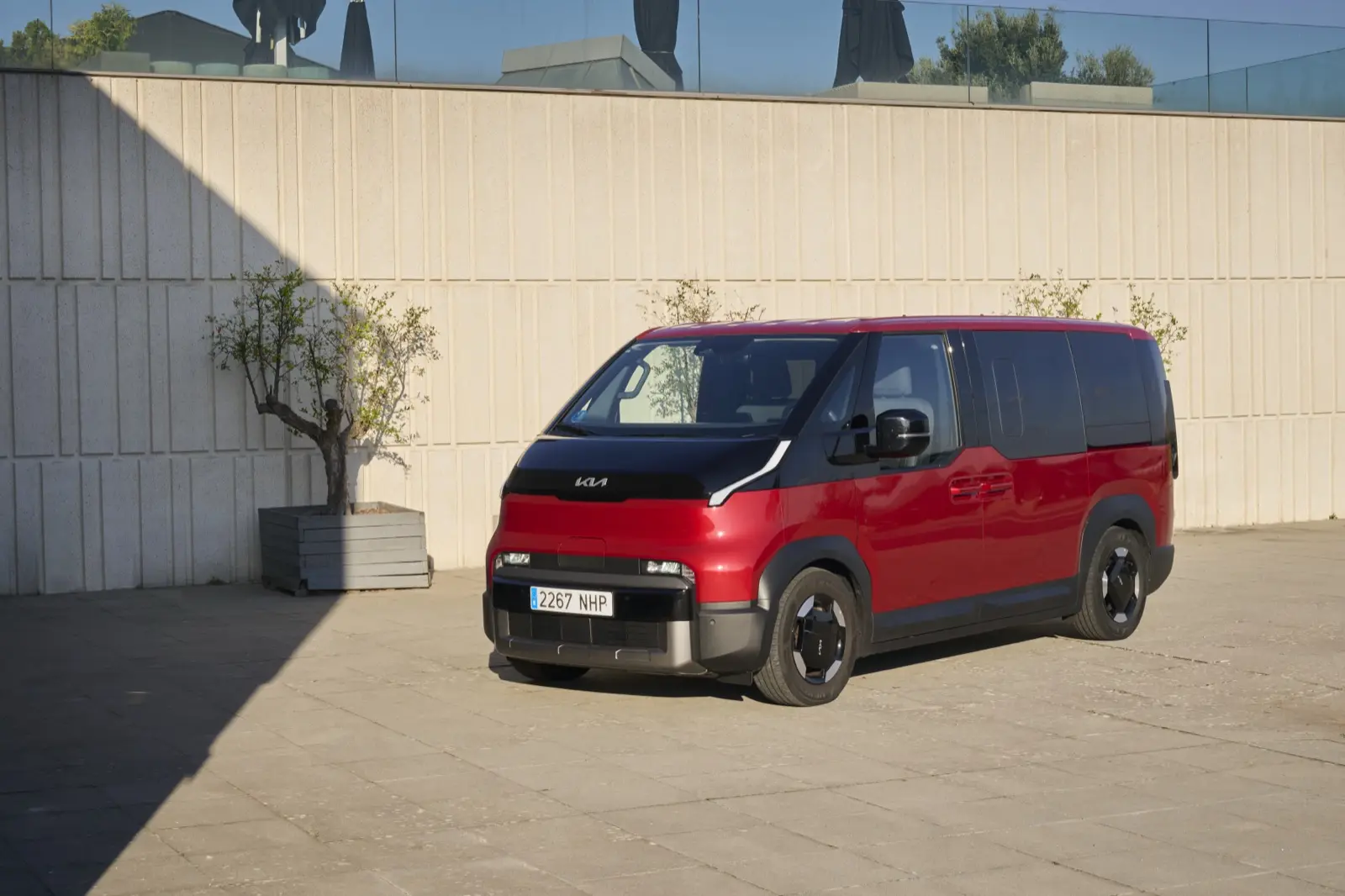 Furgoneta eléctrica de pasajeros roja aparcada junto a un edificio