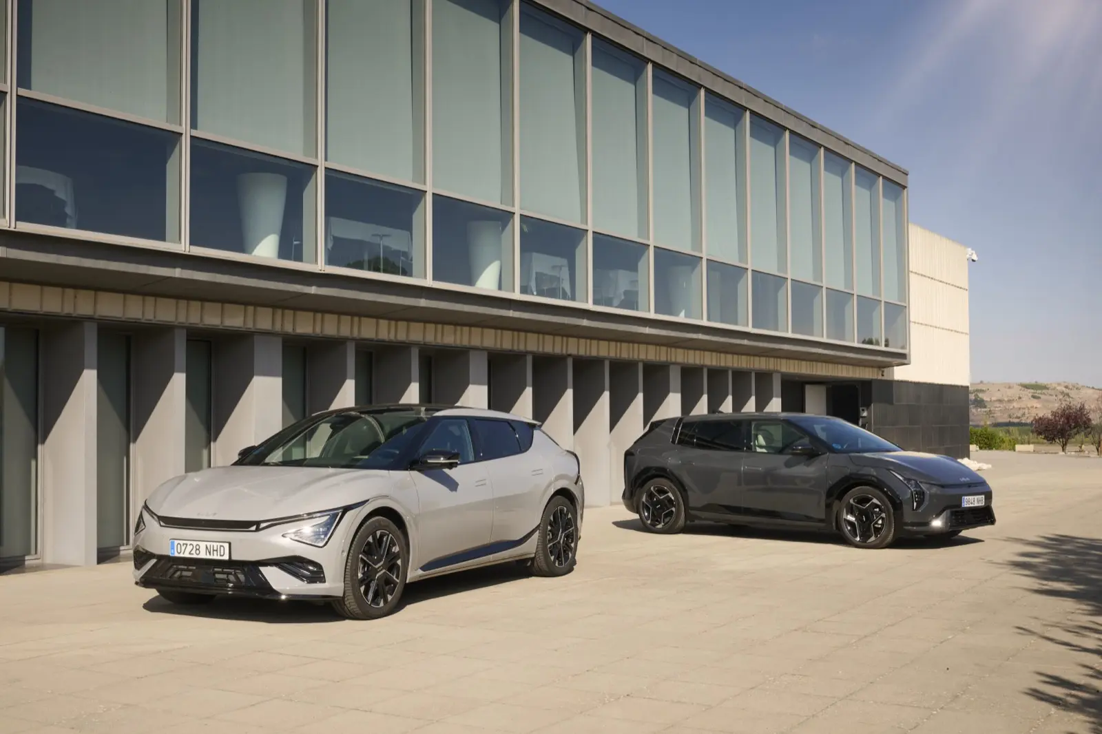 Dos modelos eléctricos de Kia aparcados frente a un edificio